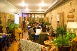 People gathered around tables for a workshop in the warm, plant-filled room