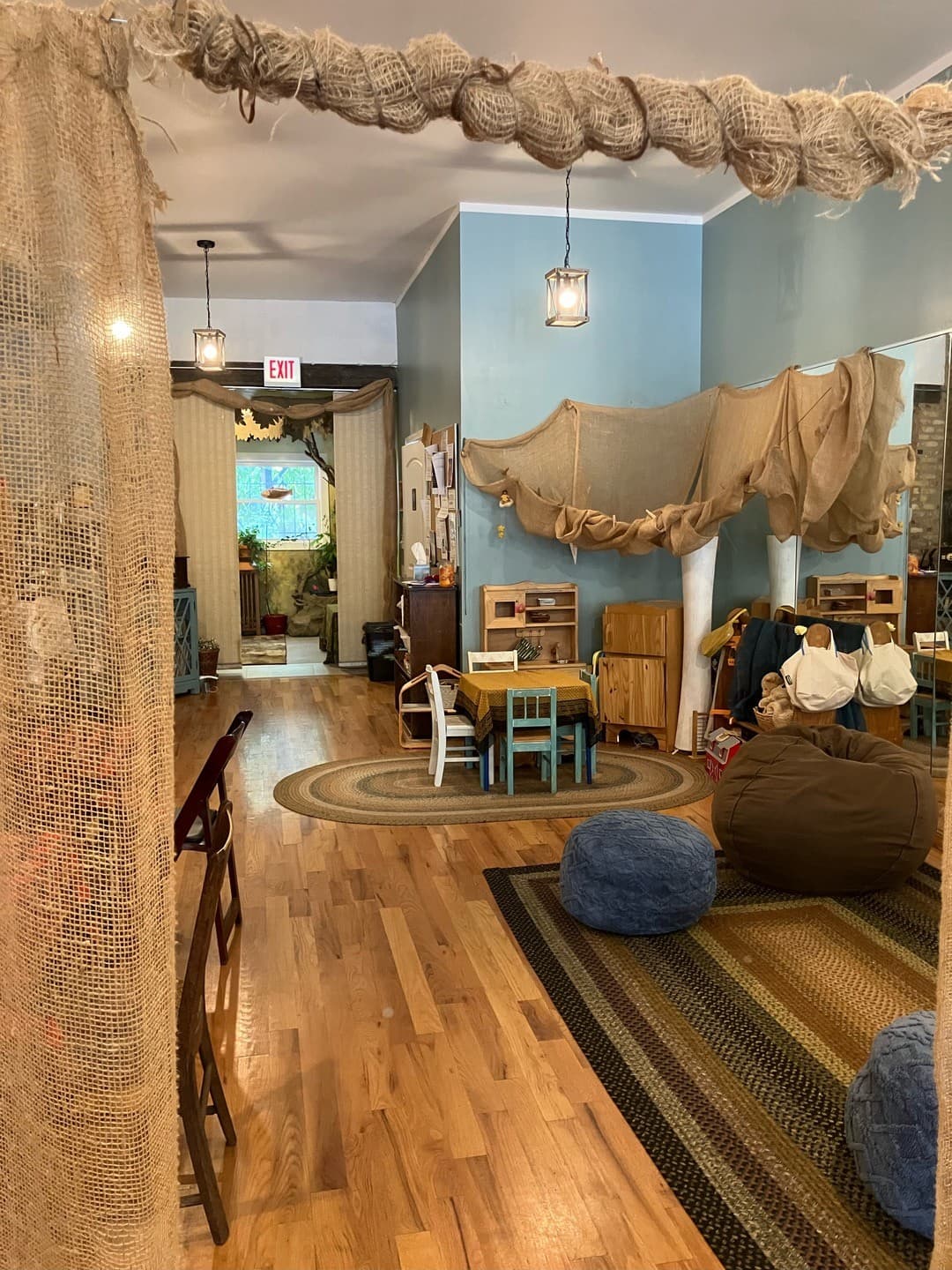 The main gathering room with a burlap canopy, children's table, and cozy floor cushions